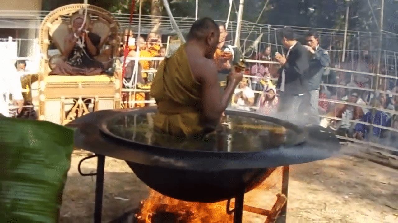 رجل بوذي يظهر تحت النار في قدر به زيت ساخن