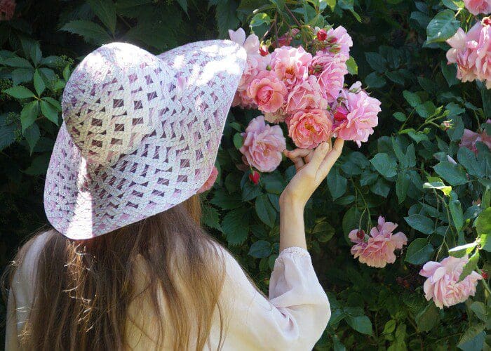 فتاة في الحديقة تضع قبعة بيضاء