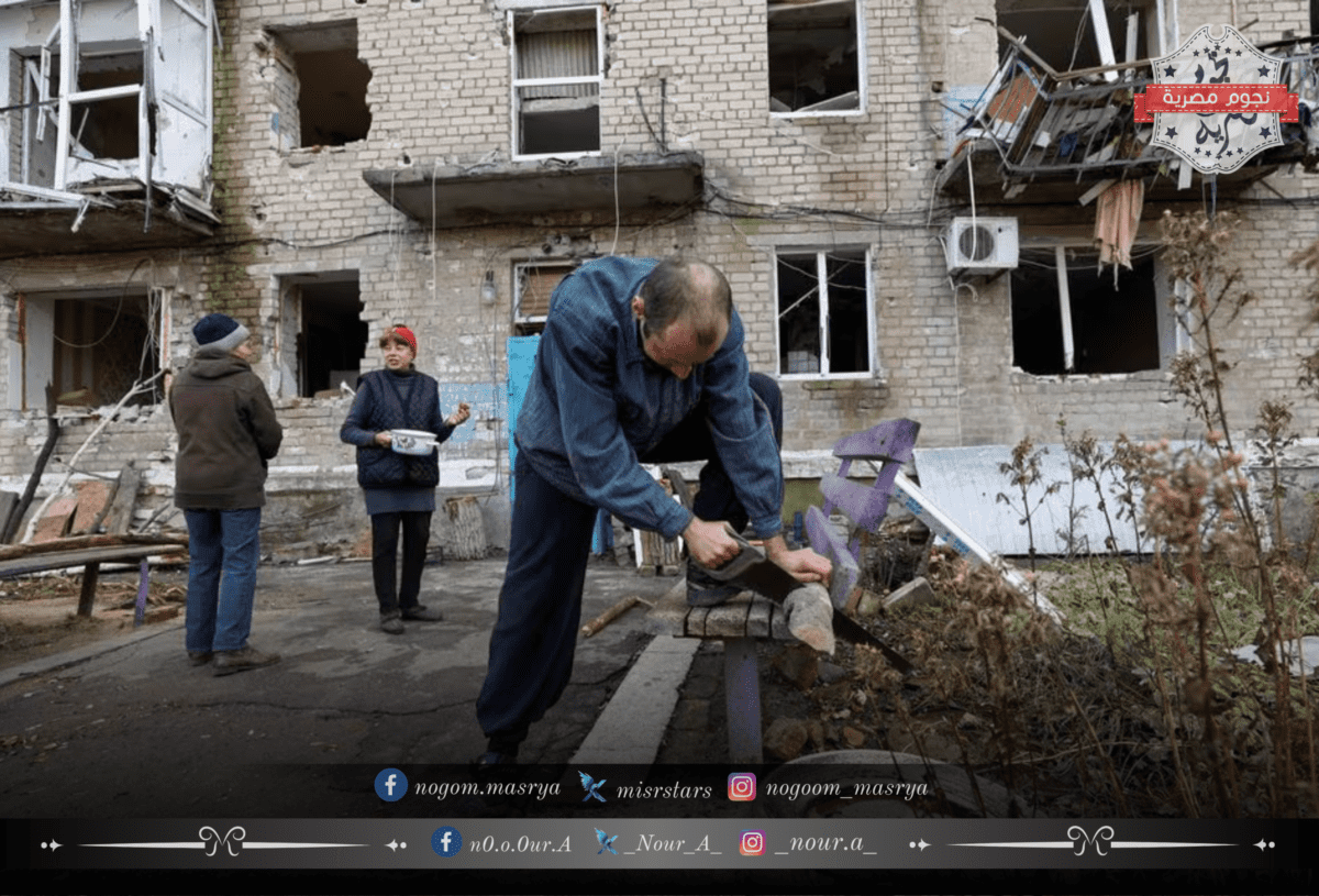  أحد السكان المحليين يقطع الحطب بجوار مبناه السكني الذي تضرر من الضربات العسكرية الروسية في بلدة أفدييفكا - مصدر الصورة: موقع Reuters
